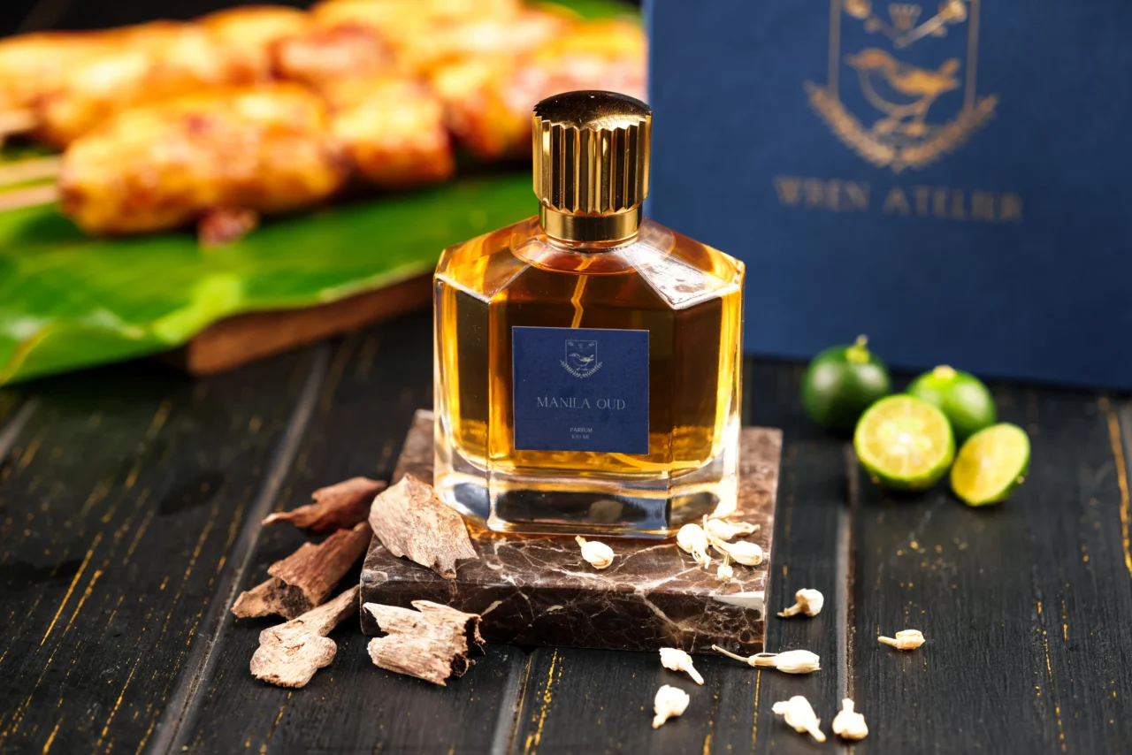 A bottle of Wren Atelier perfume on a table beside an assortment of food items.